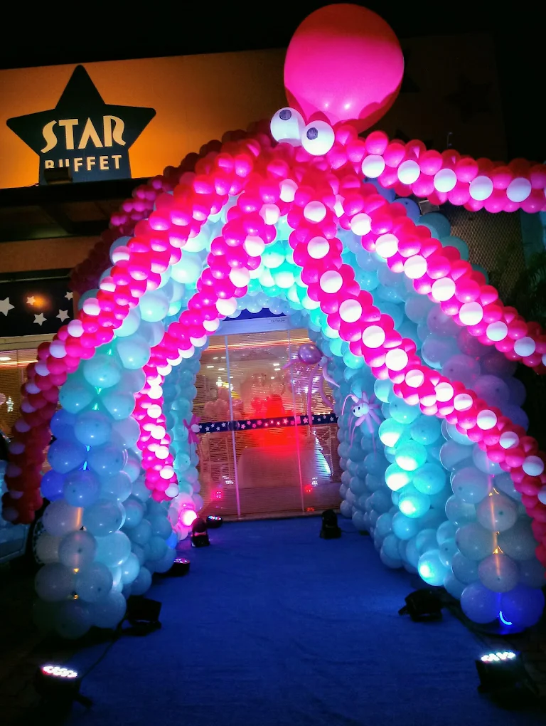 Entrada do Star Buffet com arco de balões iluminado e o letreiro da casa