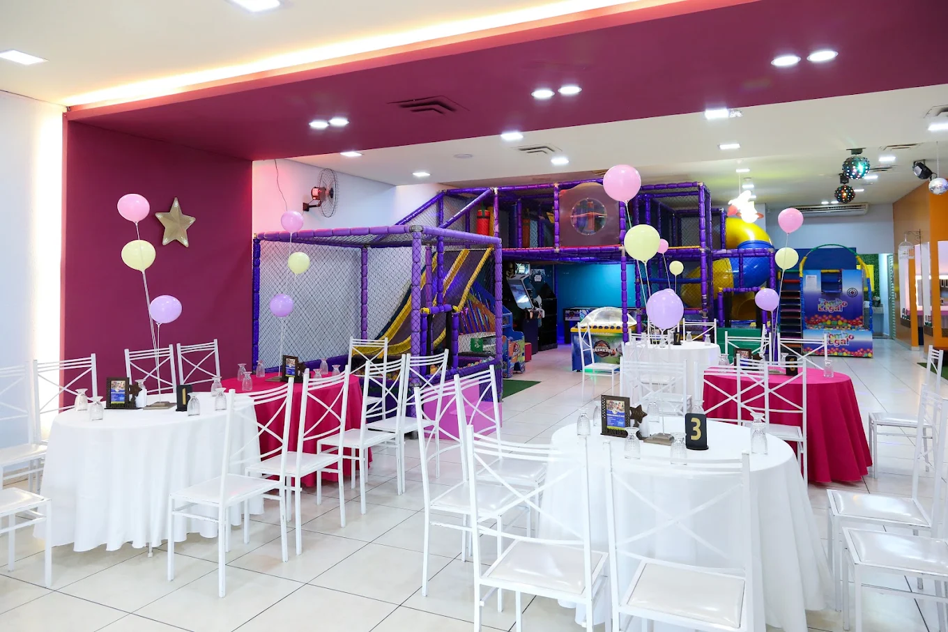 Salão do Star Buffet montado com mesas redondas e a área de brinquedos ao fundo